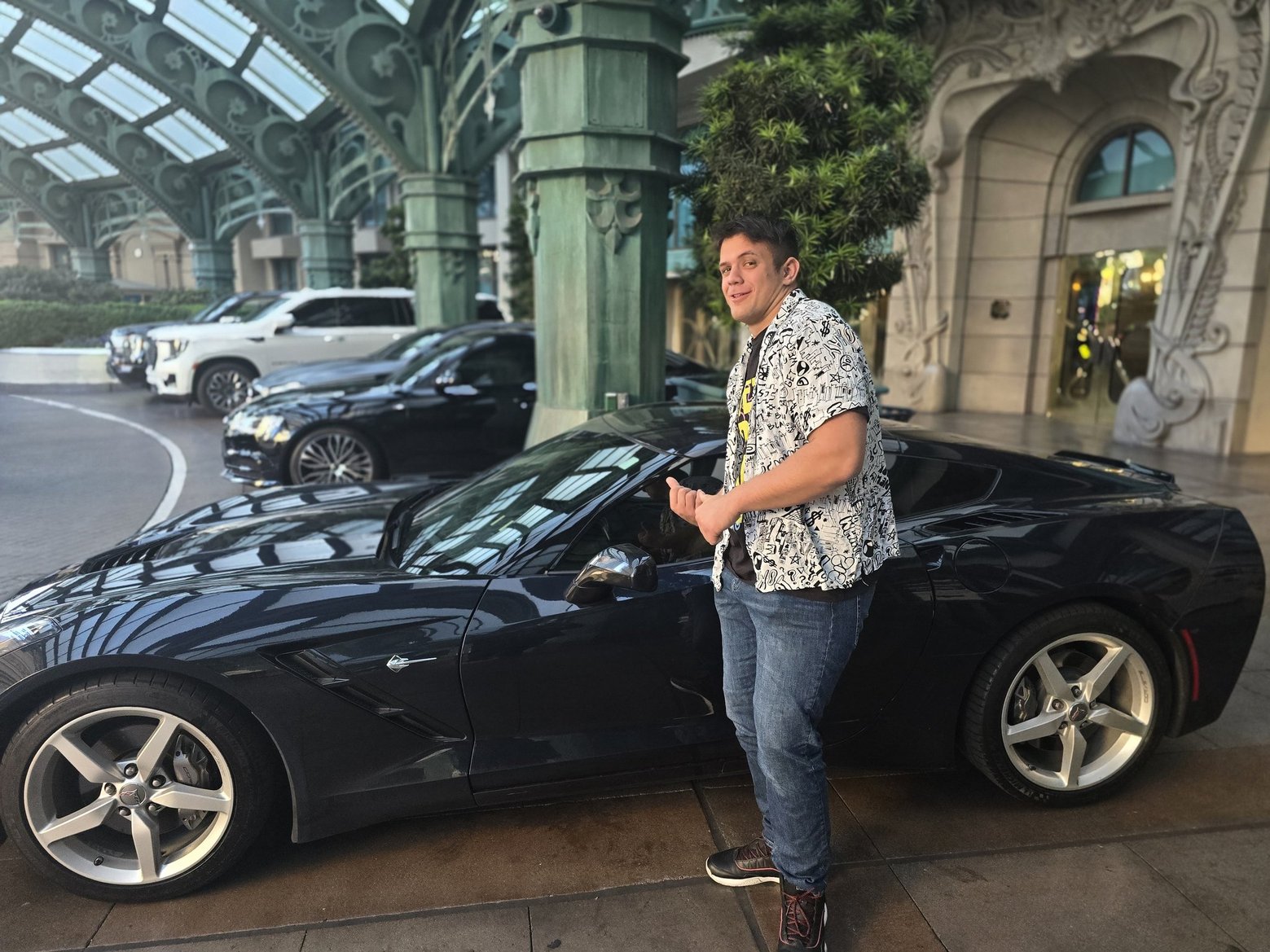 John's Automotive technician beside a black Corvette