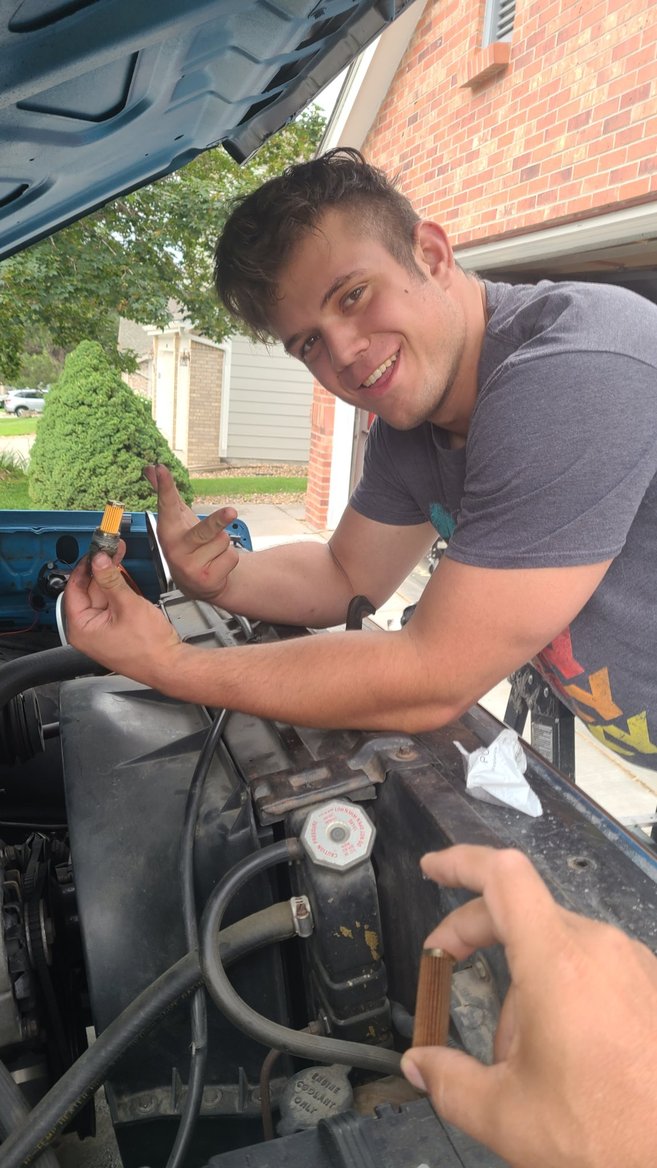 John's Automotive mechanic performing a mobile pre-purchase vehicle inspection under the hood